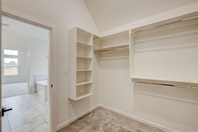 spacious closet featuring lofted ceiling, visible vents, and marble finish floor