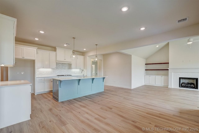 kitchen featuring white cabinets, tasteful backsplash, visible vents, and light countertops