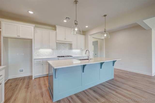 kitchen with a sink, gas cooktop, light countertops, white cabinetry, and visible vents