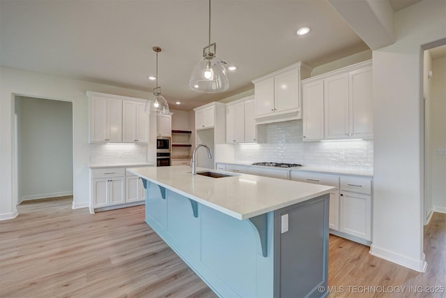kitchen featuring recessed lighting, gas cooktop, a sink, light wood-style flooring, and tasteful backsplash