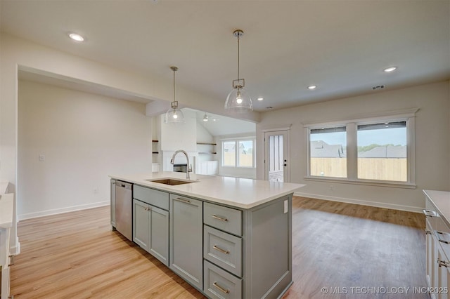 kitchen with light wood finished floors, dishwasher, a sink, gray cabinetry, and open floor plan