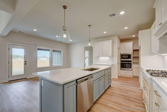 kitchen with light wood finished floors, stainless steel appliances, a sink, visible vents, and gray cabinets