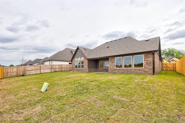 rear view of property with brick siding, a lawn, board and batten siding, and a fenced backyard