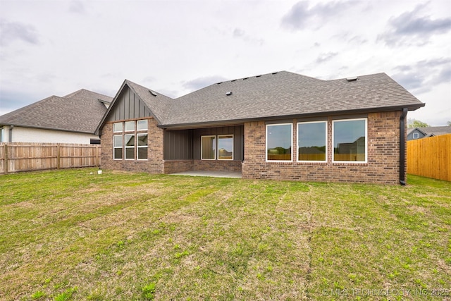 rear view of house featuring a patio area, a lawn, board and batten siding, a fenced backyard, and brick siding
