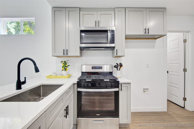 kitchen featuring gray cabinetry, sink, stainless steel appliances, and light hardwood / wood-style flooring