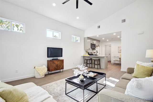 living room with ceiling fan, light wood-type flooring, and high vaulted ceiling