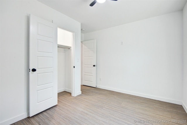 unfurnished bedroom featuring ceiling fan, a closet, and light wood-type flooring