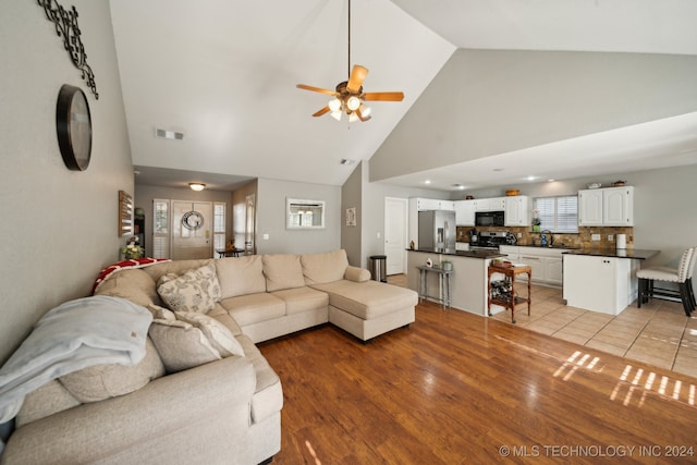 living room with high vaulted ceiling, a fireplace, hardwood / wood-style flooring, and ceiling fan