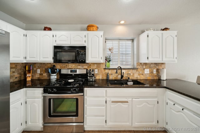 kitchen featuring light tile patterned flooring, a fireplace, vaulted ceiling, white cabinets, and dishwasher