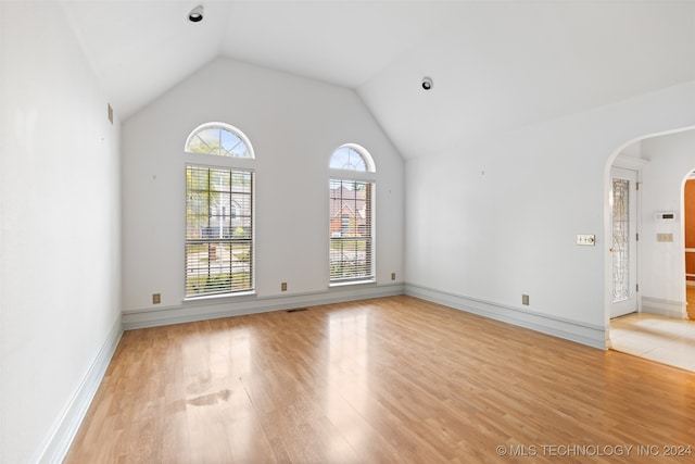 spare room with light hardwood / wood-style flooring and lofted ceiling