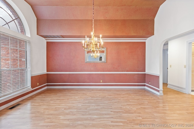 unfurnished dining area featuring hardwood / wood-style floors, a chandelier, and high vaulted ceiling