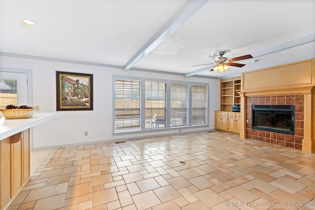 unfurnished living room with a fireplace, ceiling fan, beam ceiling, and built in features