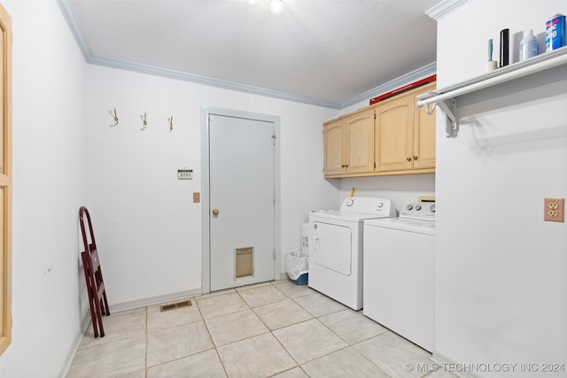 clothes washing area featuring ornamental molding, a textured ceiling, cabinets, and washer and clothes dryer