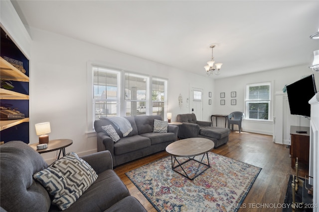 living room with a wall unit AC, a wealth of natural light, dark hardwood / wood-style flooring, and a notable chandelier