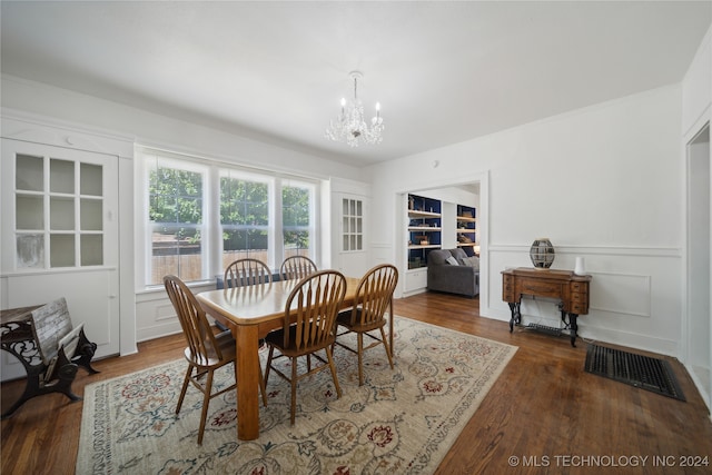 dining area with dark wood-type flooring and an inviting chandelier