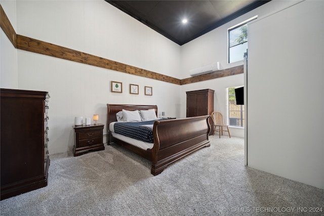 bedroom with a wall mounted AC, carpet floors, ornamental molding, and a high ceiling