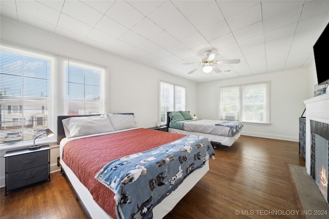 bedroom with a fireplace, ceiling fan, cooling unit, and dark wood-type flooring