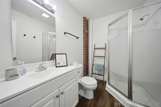 bathroom featuring toilet, vanity, hardwood / wood-style floors, and a shower with door