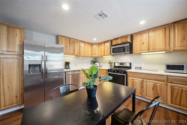 kitchen with appliances with stainless steel finishes and dark hardwood / wood-style flooring