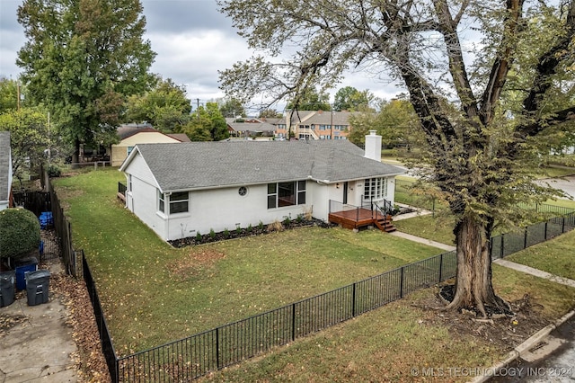 ranch-style home with a chimney, stucco siding, a shingled roof, a fenced backyard, and a front lawn