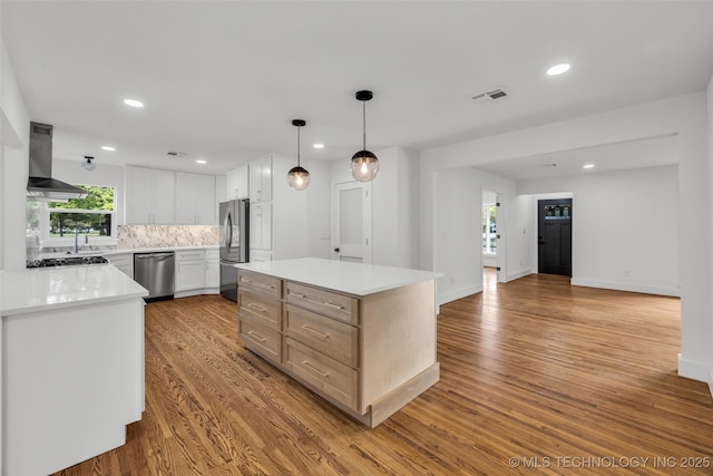 kitchen featuring refrigerator, visible vents, wall chimney range hood, backsplash, and dishwasher