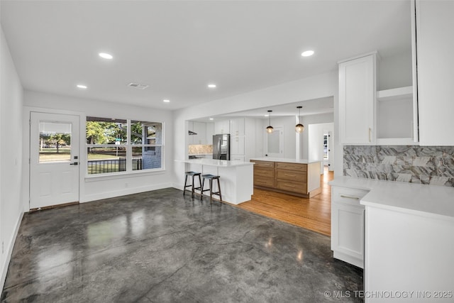 kitchen featuring finished concrete flooring, visible vents, white cabinets, and freestanding refrigerator