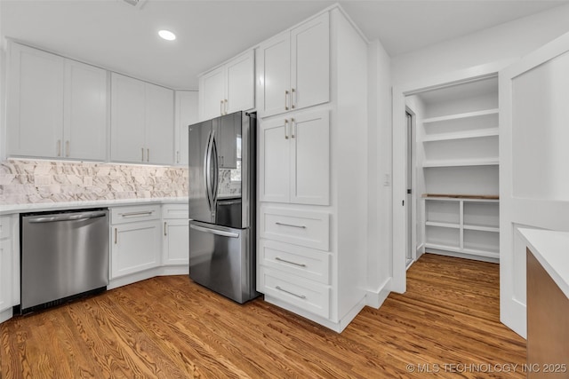 kitchen featuring stainless steel appliances, recessed lighting, light countertops, white cabinets, and light wood-type flooring