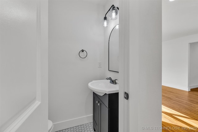 bathroom with toilet, vanity, and baseboards