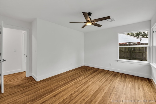 unfurnished room featuring visible vents, baseboards, and wood finished floors