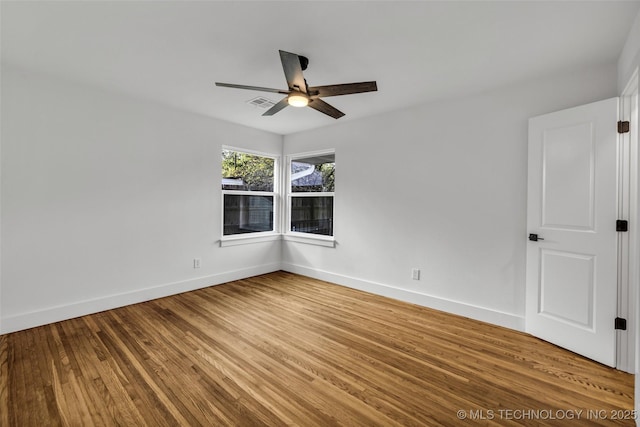 spare room featuring visible vents, ceiling fan, baseboards, and wood finished floors