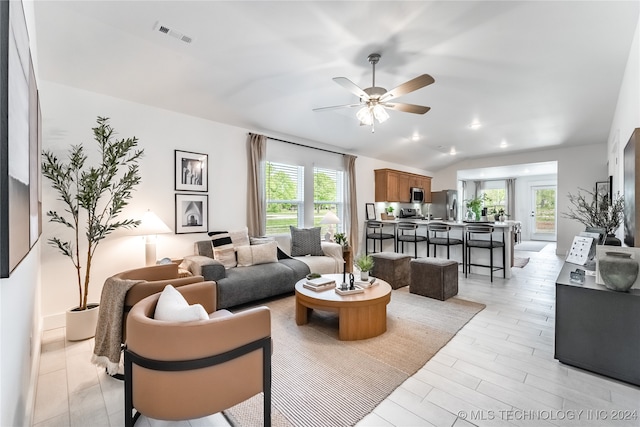 living room with light wood-type flooring, ceiling fan, and vaulted ceiling