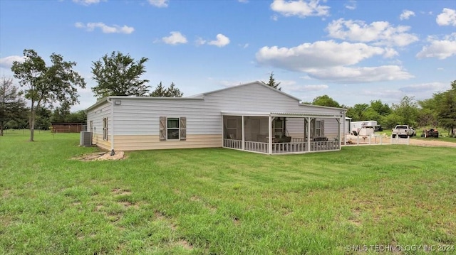 rear view of house with a sunroom, a yard, and central AC