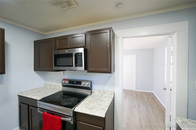 kitchen with light wood-type flooring, dark brown cabinets, crown molding, and stainless steel appliances