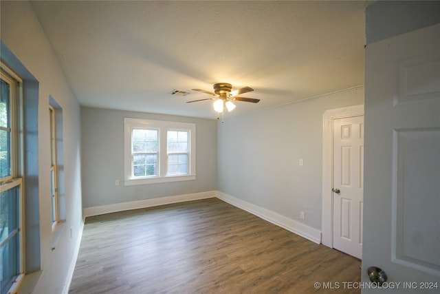 empty room with ceiling fan and dark hardwood / wood-style flooring