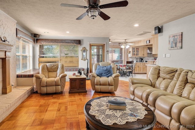 living room featuring ceiling fan, a textured ceiling, and light parquet flooring