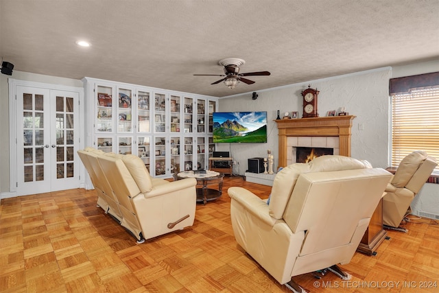 living room featuring french doors, a tiled fireplace, a textured ceiling, ceiling fan, and light parquet flooring