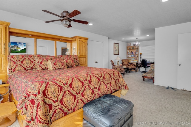 carpeted bedroom with ceiling fan with notable chandelier and a textured ceiling