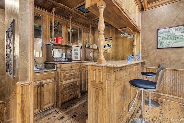 bar with light stone countertops, dark hardwood / wood-style floors, wooden walls, and coffered ceiling