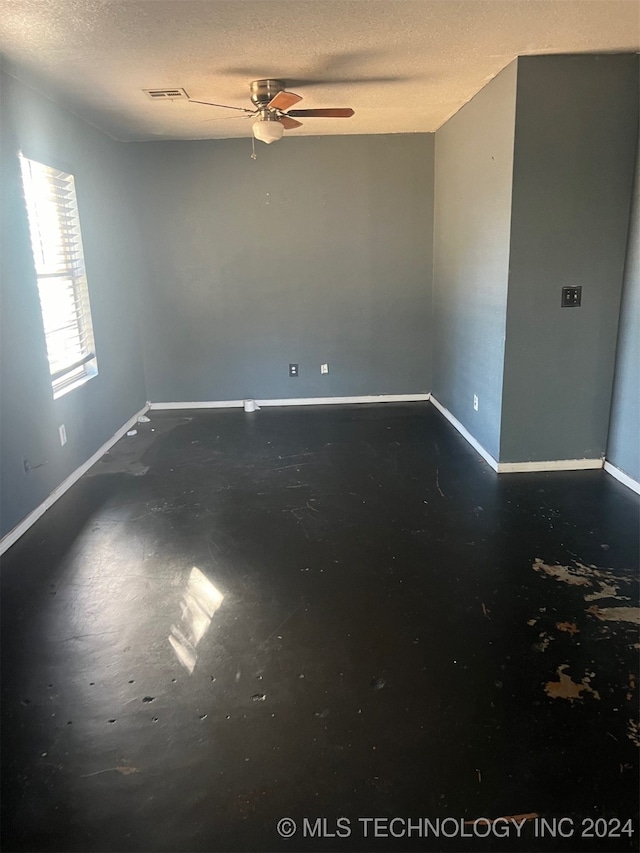 unfurnished room with ceiling fan and a textured ceiling