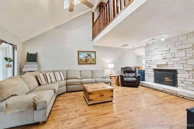 living room featuring a fireplace, wood-type flooring, a textured ceiling, and vaulted ceiling