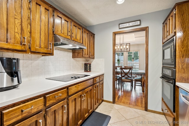 kitchen featuring black appliances, a textured ceiling, light tile patterned floors, an inviting chandelier, and decorative light fixtures