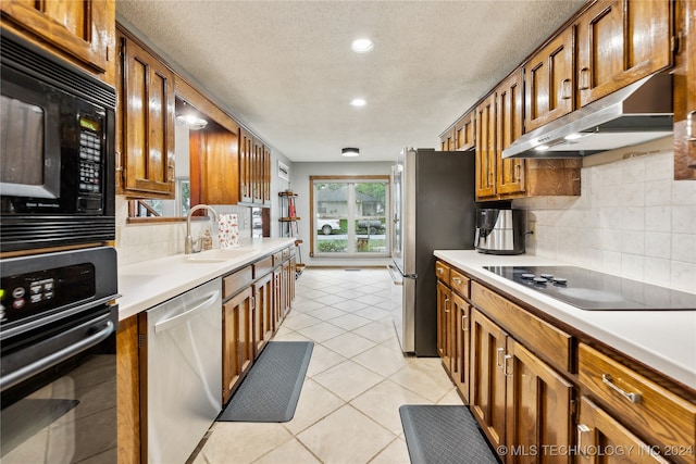 kitchen with black appliances, decorative backsplash, sink, and light tile patterned flooring