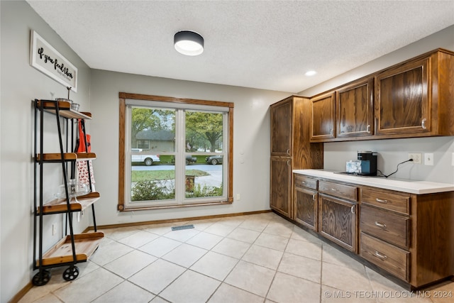 kitchen with dark brown cabinets, a textured ceiling, and light tile patterned floors