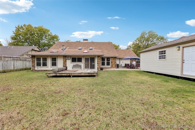 rear view of property with a deck, central air condition unit, a yard, and a patio area