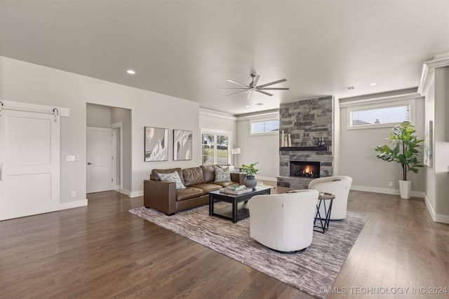 living room with a stone fireplace, ceiling fan, and dark wood-type flooring