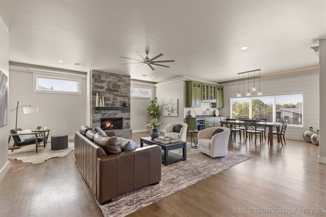 living room featuring a stone fireplace, ceiling fan, and hardwood / wood-style floors