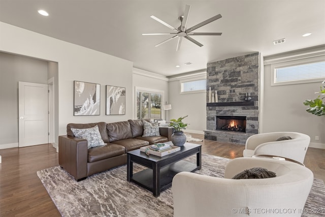 living room featuring dark hardwood / wood-style floors, ceiling fan, ornamental molding, and a fireplace