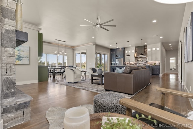 living room with dark hardwood / wood-style floors, ceiling fan, and ornamental molding