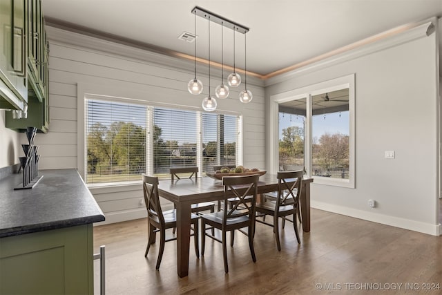 dining area featuring wooden walls, dark wood-type flooring, and ornamental molding