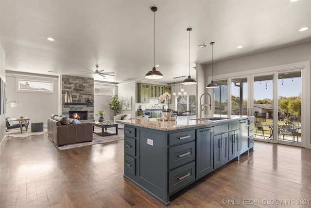 kitchen featuring pendant lighting, a kitchen island with sink, ceiling fan, dark hardwood / wood-style floors, and light stone countertops